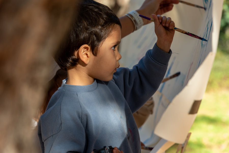 Child painting on an easel at an outdoor birthday party