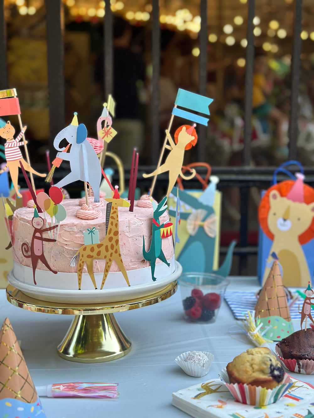 Kids' party table with an animal-themed birthday cake and paper party decorations