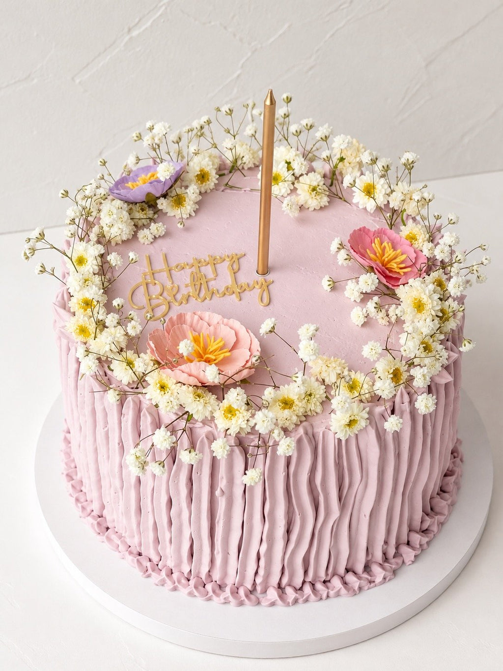 6-inch lilac birthday cake with ruffled frosting sides, a baby's breath wreath and a gold happy birthday topper