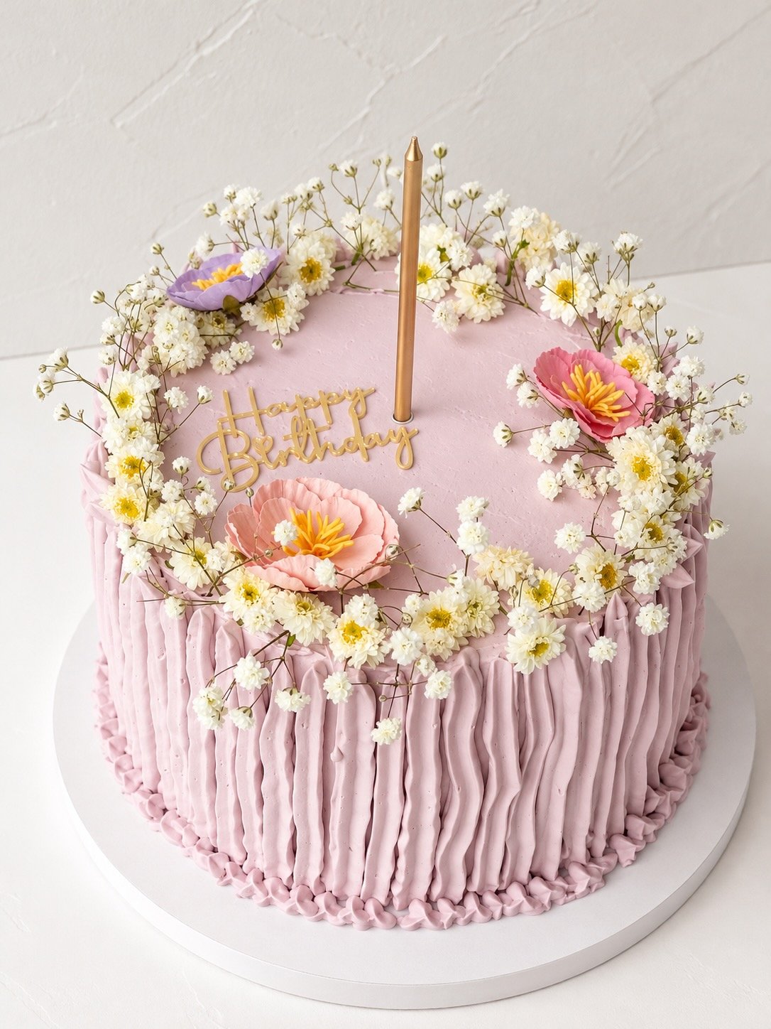 6-inch lilac birthday cake with ruffled frosting sides, a baby's breath wreath and a gold happy birthday topper
