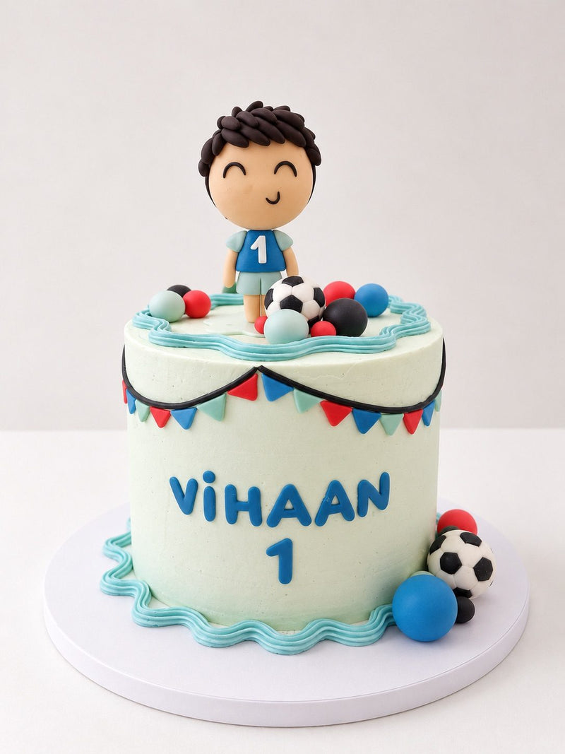 Handmade fondant footballer on a first birthday cake