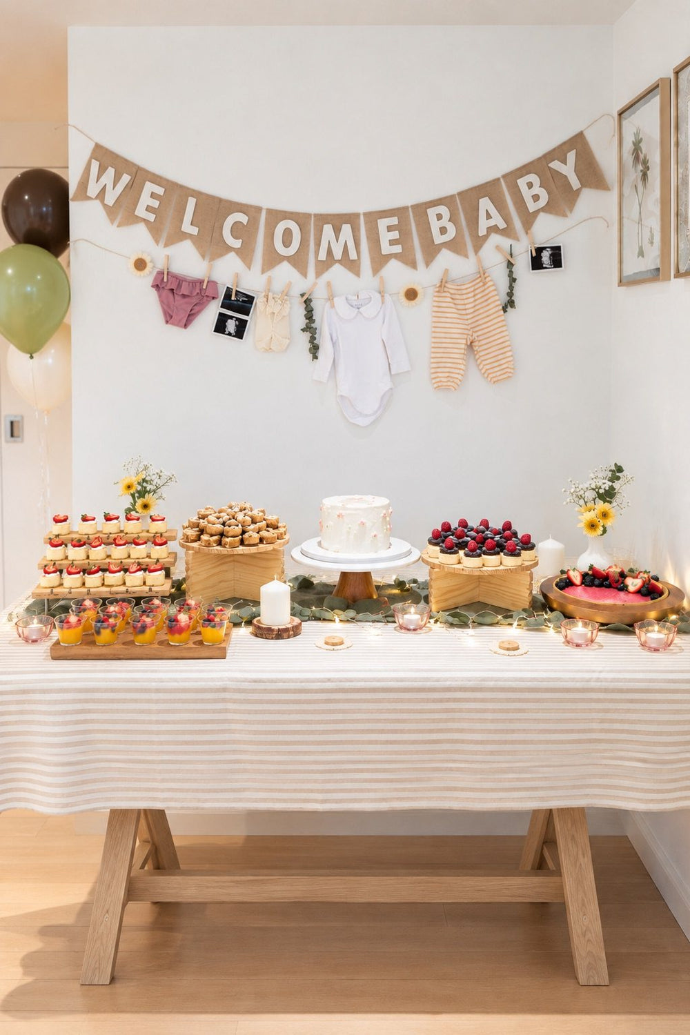 Welcome baby dessert table with cakes, treats and a garland