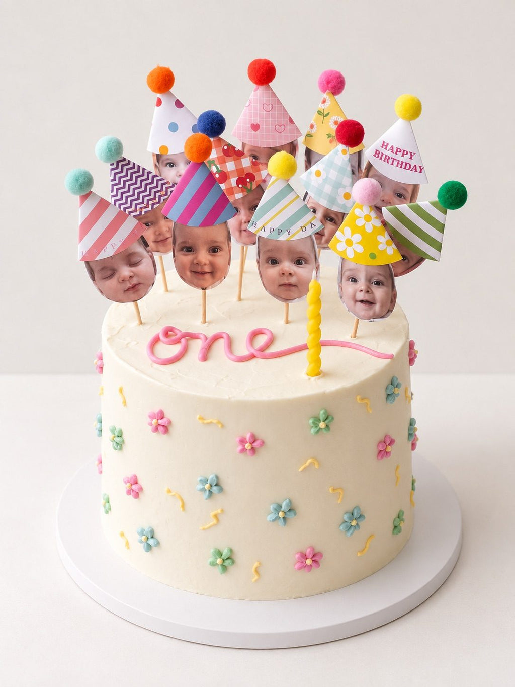 Tall 6-inch one birthday cake with pastel piped flowers and party hat toppers